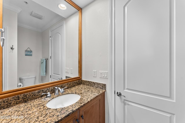 half bathroom featuring vanity, ornamental molding, and toilet