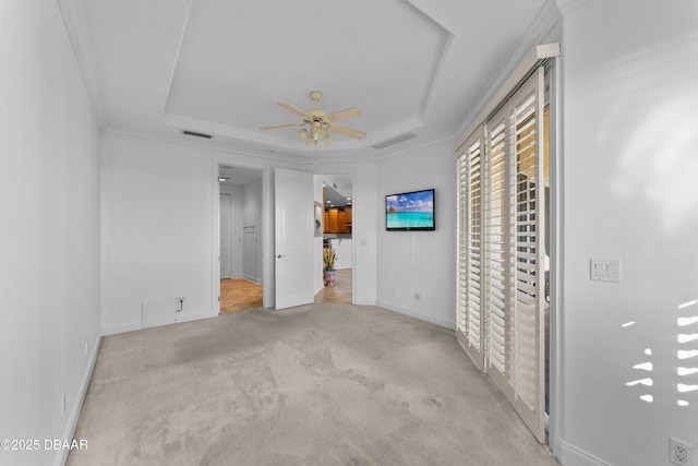 unfurnished bedroom with a tray ceiling, light colored carpet, ornamental molding, and visible vents