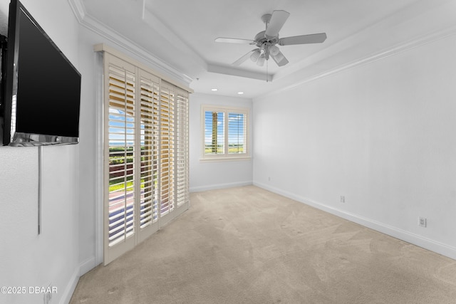 unfurnished room with carpet flooring, crown molding, ceiling fan, a raised ceiling, and baseboards