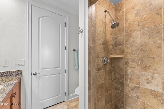 bathroom featuring toilet, tiled shower, and vanity
