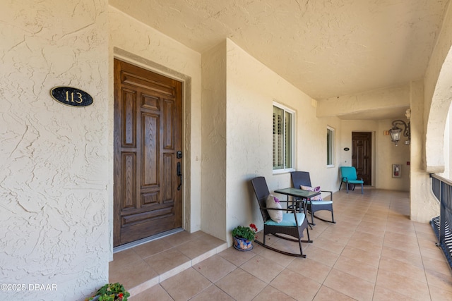 property entrance with covered porch and stucco siding