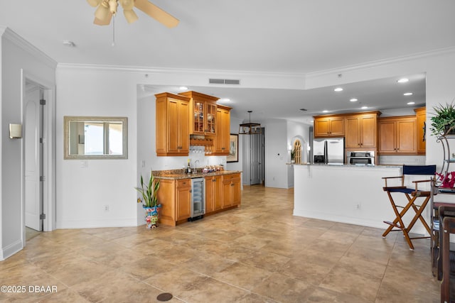 kitchen featuring visible vents, beverage cooler, ornamental molding, stainless steel appliances, and recessed lighting