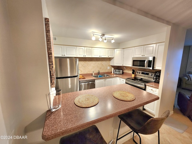 2800 N Atlantic Ave Unit 1006, Daytona Beach, FL 32118 - kitchen featuring appliances with stainless steel finishes, tasteful backsplash, white cabinetry, a breakfast bar area, and a peninsula