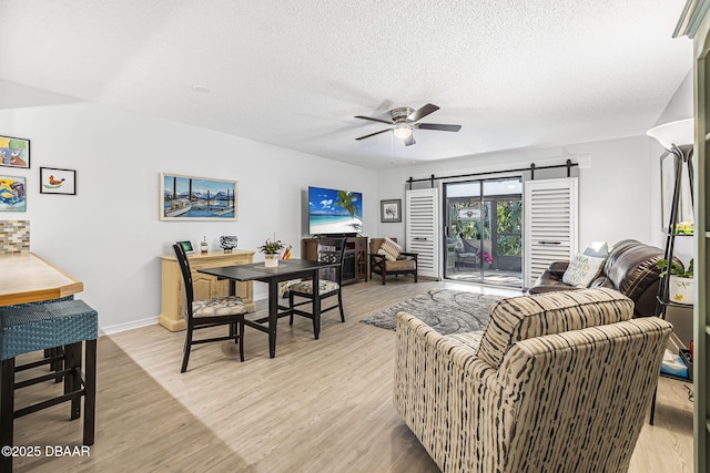 living room featuring a textured ceiling, light hardwood / wood-style flooring, and ceiling fan