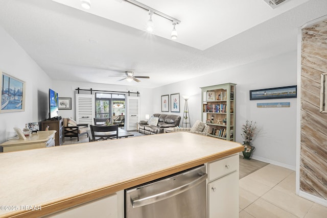 kitchen featuring ceiling fan, rail lighting, stainless steel dishwasher, a textured ceiling, and light tile patterned floors