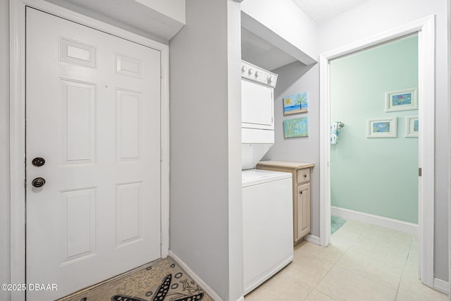 laundry room featuring cabinets, light tile patterned floors, and stacked washing maching and dryer