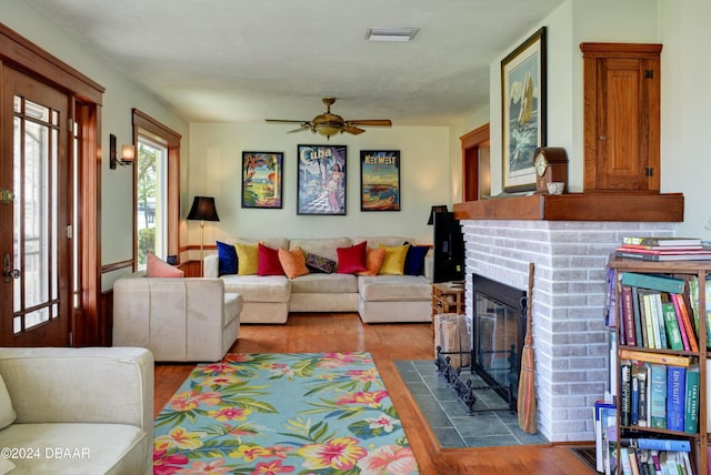 living room featuring hardwood / wood-style floors, ceiling fan, and a fireplace