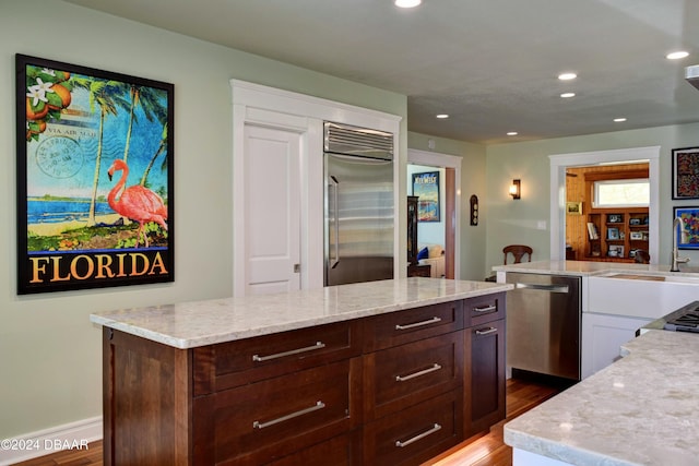 kitchen featuring a center island, sink, dark brown cabinetry, wood-type flooring, and stainless steel appliances