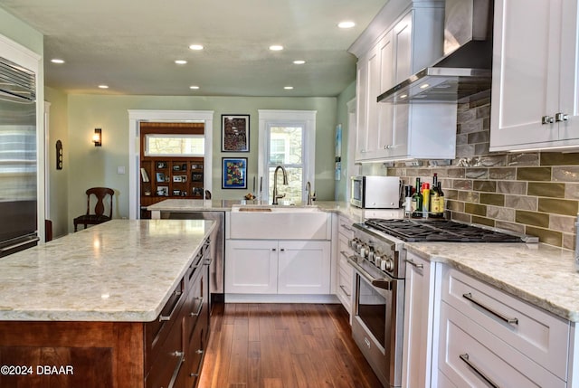 kitchen featuring white cabinets, appliances with stainless steel finishes, dark hardwood / wood-style floors, and wall chimney exhaust hood