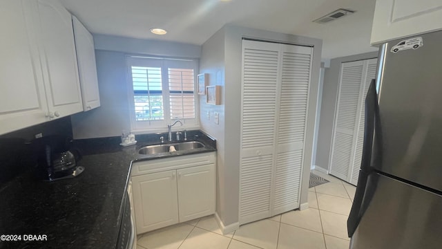 kitchen with white cabinets, light tile patterned floors, sink, and stainless steel fridge