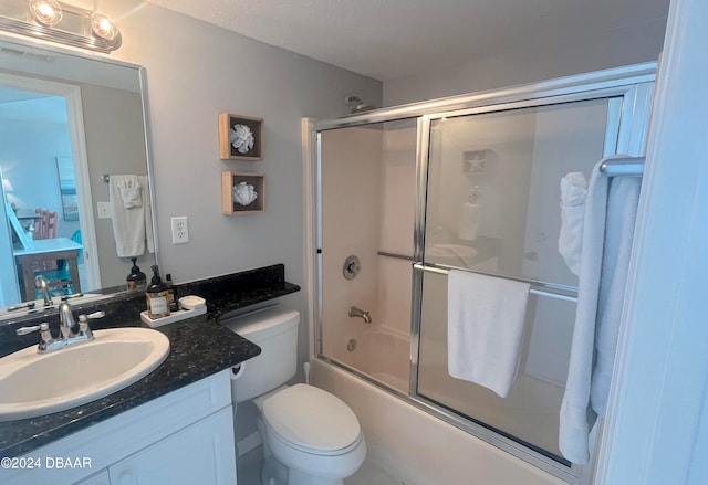 full bathroom with bath / shower combo with glass door, vanity, and toilet