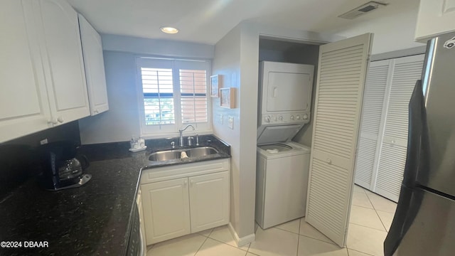 washroom featuring light tile patterned floors, stacked washer and clothes dryer, and sink