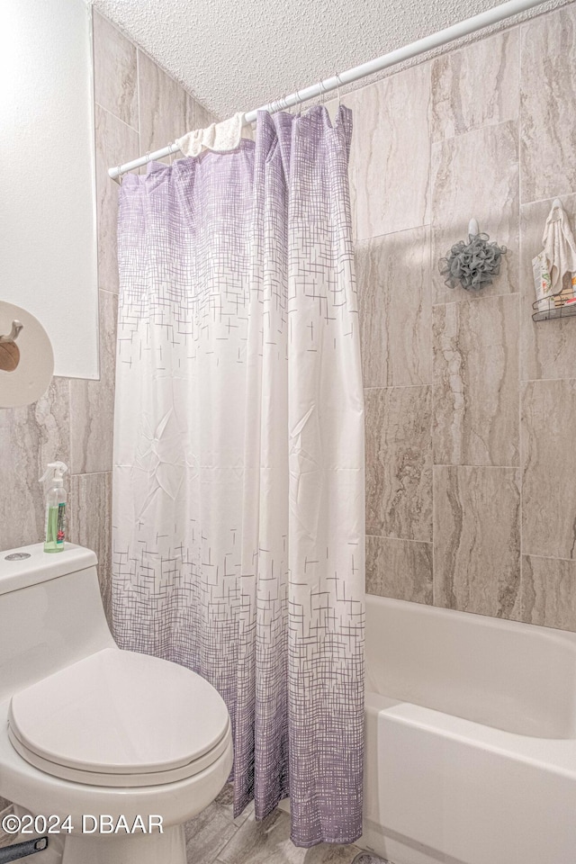 bathroom with toilet, shower / bath combo, tile walls, and a textured ceiling