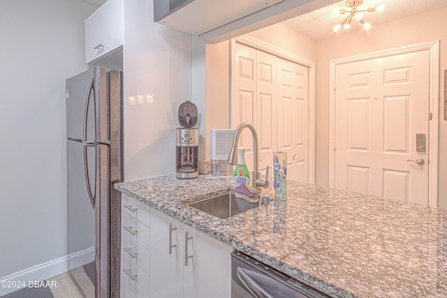 1401 S Palmetto Ave Unit 318, Daytona Beach, FL 32114 - kitchen featuring a sink, appliances with stainless steel finishes, white cabinetry, light wood-style flooring, and baseboards