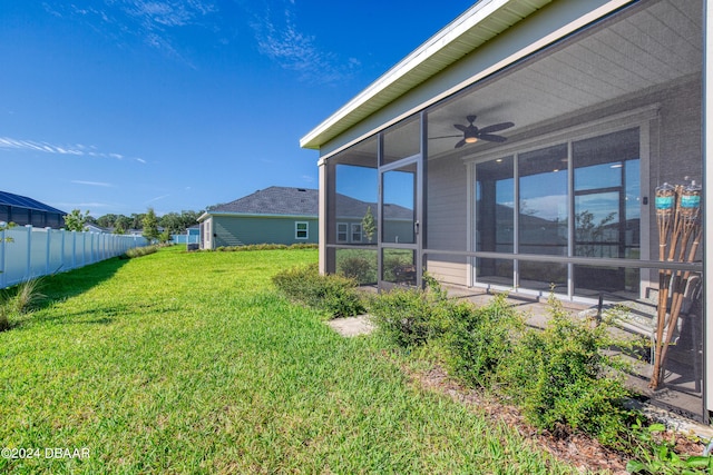 view of yard with a sunroom, ceiling fan, and fence