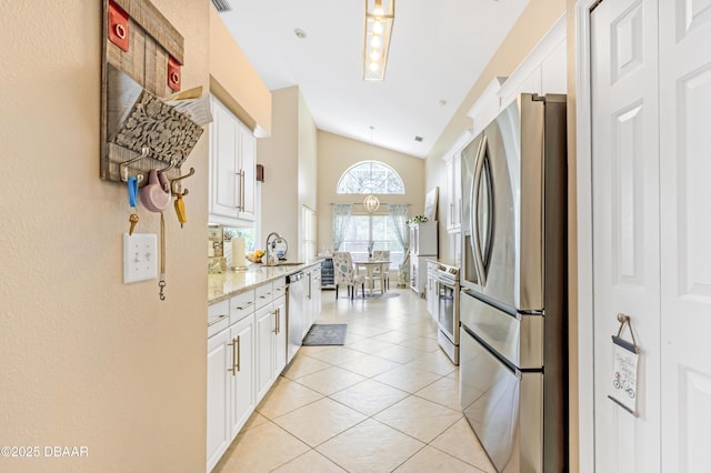 1405 Florida Moss Ln, Port Orange, FL 32128 - kitchen featuring appliances with stainless steel finishes, vaulted ceiling, white cabinetry, light tile patterned floors, and light stone countertops