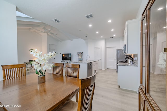 dining room featuring ceiling fan, sink, light hardwood / wood-style flooring, and lofted ceiling