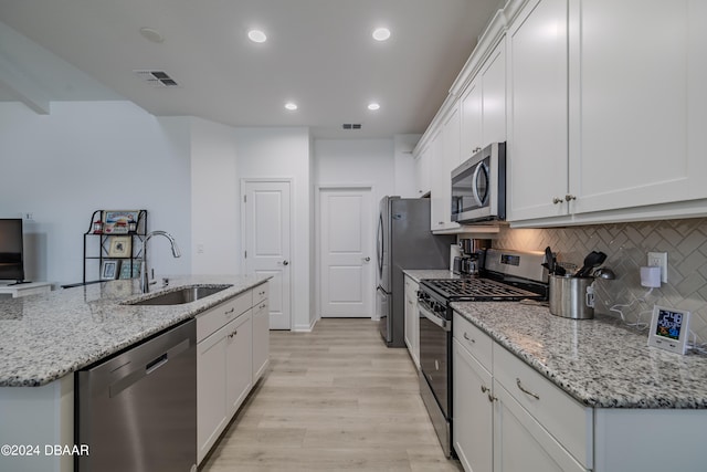 kitchen with white cabinets, sink, light hardwood / wood-style flooring, and appliances with stainless steel finishes