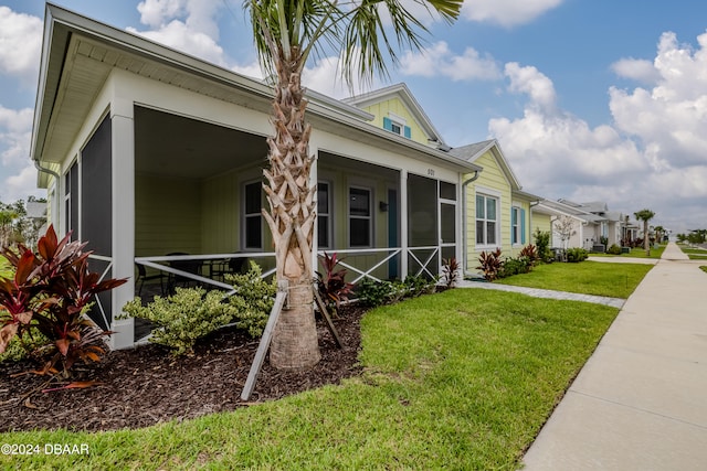 view of side of property with a lawn and a sunroom