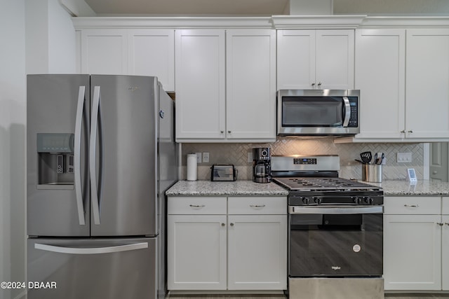 kitchen with stainless steel appliances, light stone countertops, white cabinetry, and tasteful backsplash