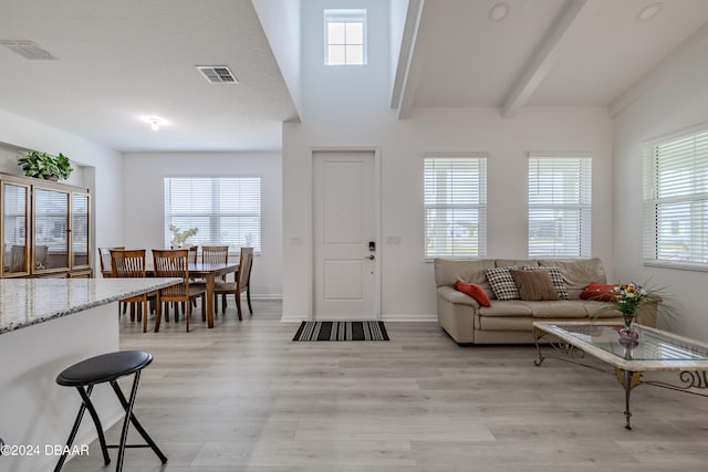 foyer entrance with light wood-type flooring, beamed ceiling, and a healthy amount of sunlight