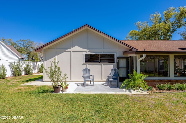 back of house featuring a patio, a shingled roof, a yard, and fence