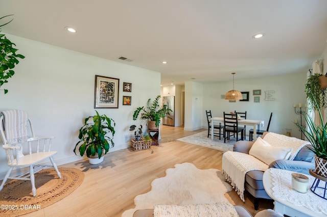 living area with light wood finished floors, visible vents, recessed lighting, and baseboards