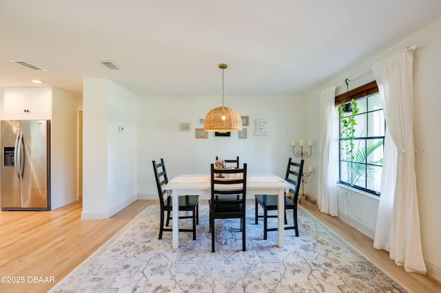 dining area featuring light wood-style flooring, baseboards, and visible vents
