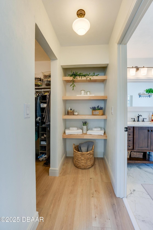 hallway with a sink, baseboards, and wood finished floors