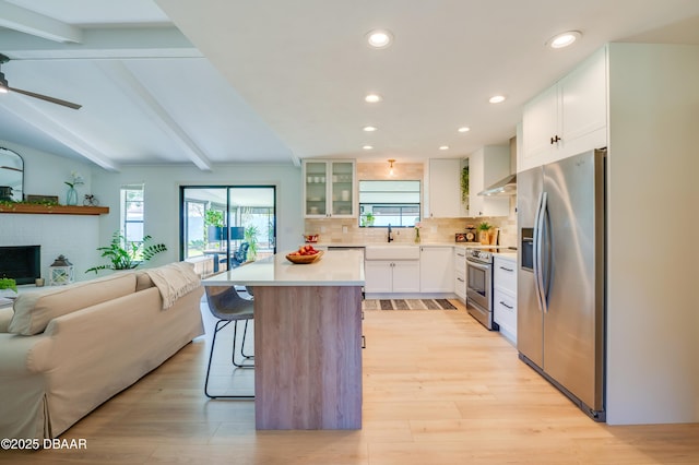 kitchen featuring a wealth of natural light, a sink, a kitchen breakfast bar, open floor plan, and stainless steel appliances