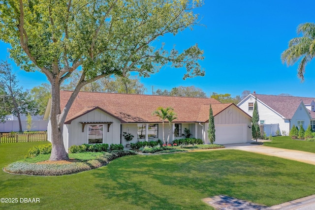 ranch-style house featuring board and batten siding, an attached garage, a front yard, and fence