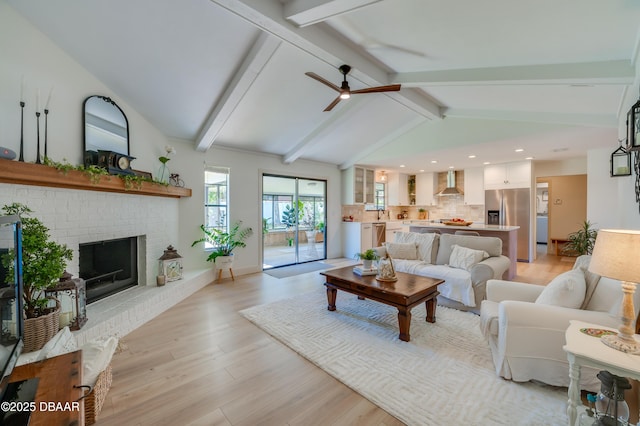 living room with light wood finished floors, vaulted ceiling with beams, recessed lighting, ceiling fan, and a brick fireplace
