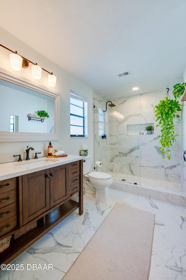 bathroom with a marble finish shower, visible vents, toilet, marble finish floor, and vanity