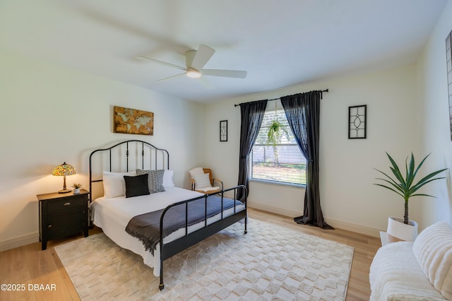 bedroom with ceiling fan, baseboards, and light wood-style flooring