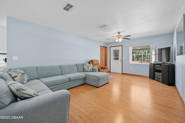 living room featuring a textured ceiling, ceiling fan, and light wood-type flooring