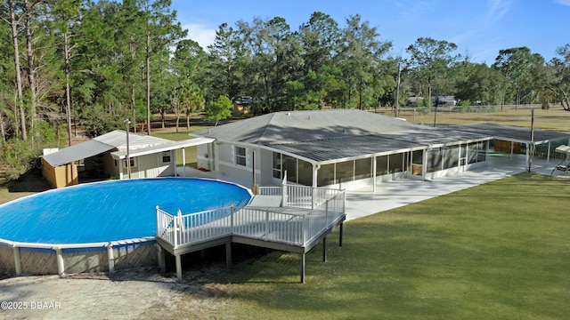 view of swimming pool featuring a sunroom and a yard