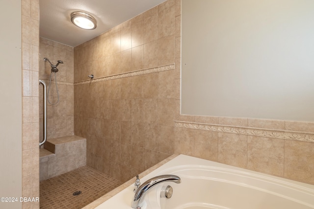 bathroom featuring a textured ceiling, tile walls, and independent shower and bath