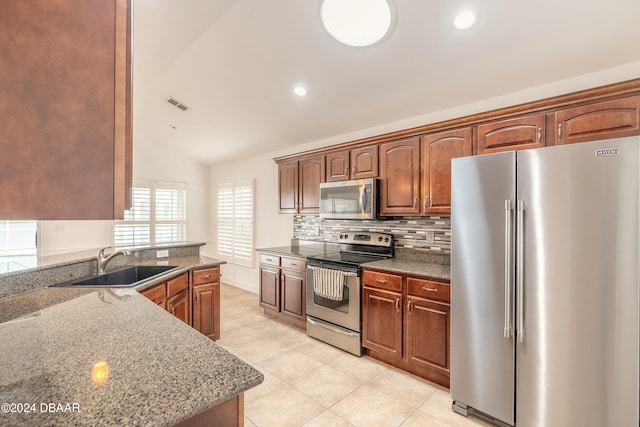 kitchen with sink, tasteful backsplash, dark stone countertops, lofted ceiling, and appliances with stainless steel finishes