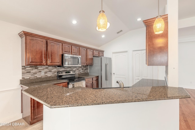 kitchen with backsplash, hanging light fixtures, vaulted ceiling, kitchen peninsula, and stainless steel appliances