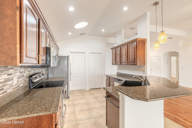 kitchen with dark stone counters, sink, hanging light fixtures, vaulted ceiling, and appliances with stainless steel finishes