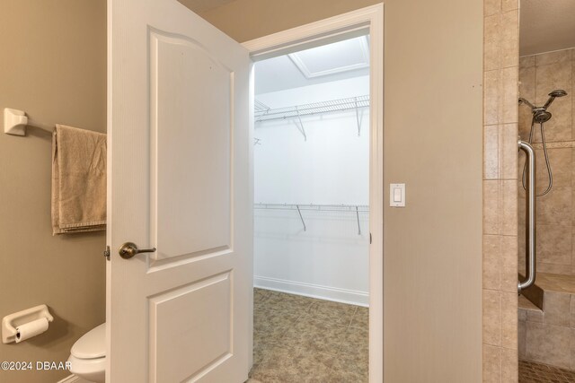 bathroom with tiled shower and toilet