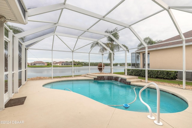 view of pool featuring glass enclosure, a patio area, and a water view