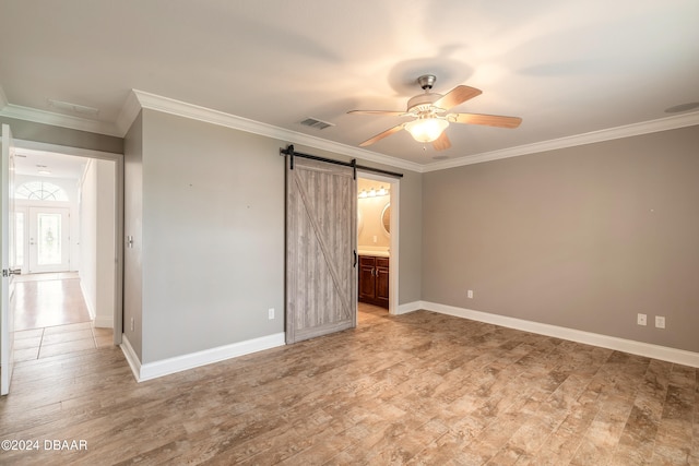 unfurnished bedroom featuring a barn door, ensuite bathroom, and ornamental molding