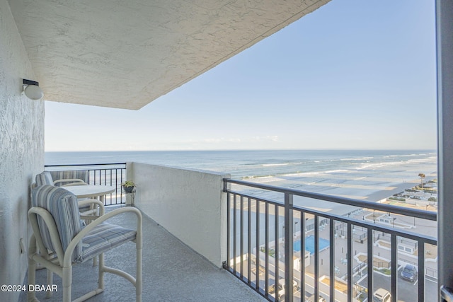 balcony with a water view and a view of the beach