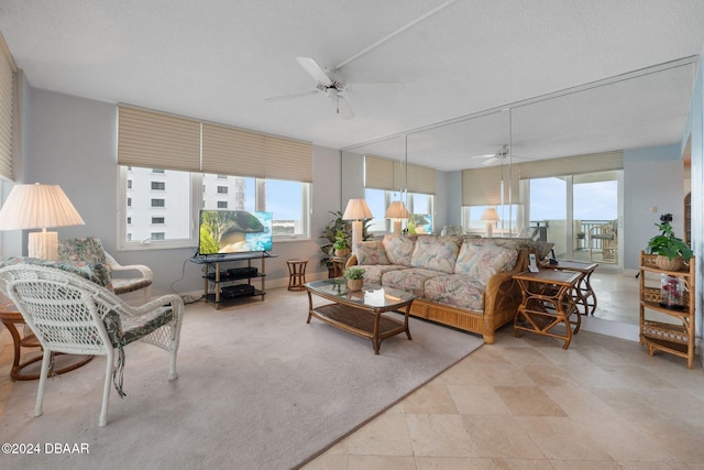 living room featuring ceiling fan, light tile patterned floors, and a textured ceiling