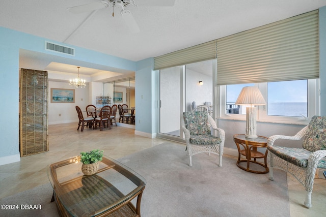 carpeted living room with ceiling fan with notable chandelier