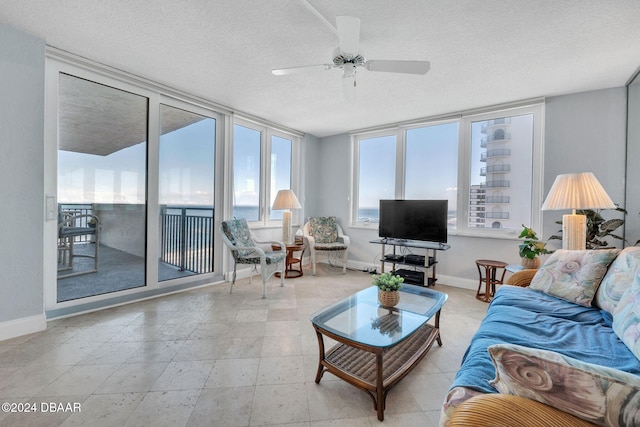 living room with ceiling fan, floor to ceiling windows, and a textured ceiling