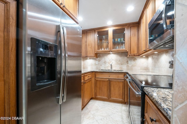 kitchen featuring sink, decorative backsplash, light stone counters, and stainless steel appliances