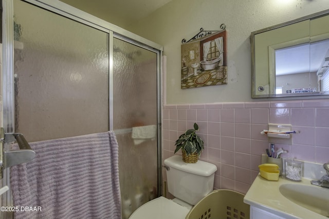 bathroom featuring vanity, toilet, tile walls, and walk in shower