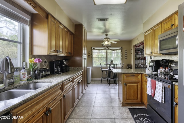 kitchen featuring electric range, sink, ceiling fan, light stone countertops, and light tile patterned flooring